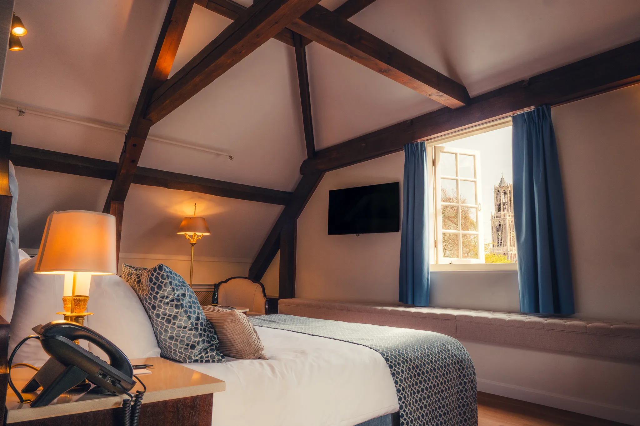 Cozy Wooden Empire Double Room bij Grand Hotel Karel V in het centrum van Utrecht met karakteristieke houten balken en uitzicht op de Domtoren, luxe hotelkamer in historische ambiance